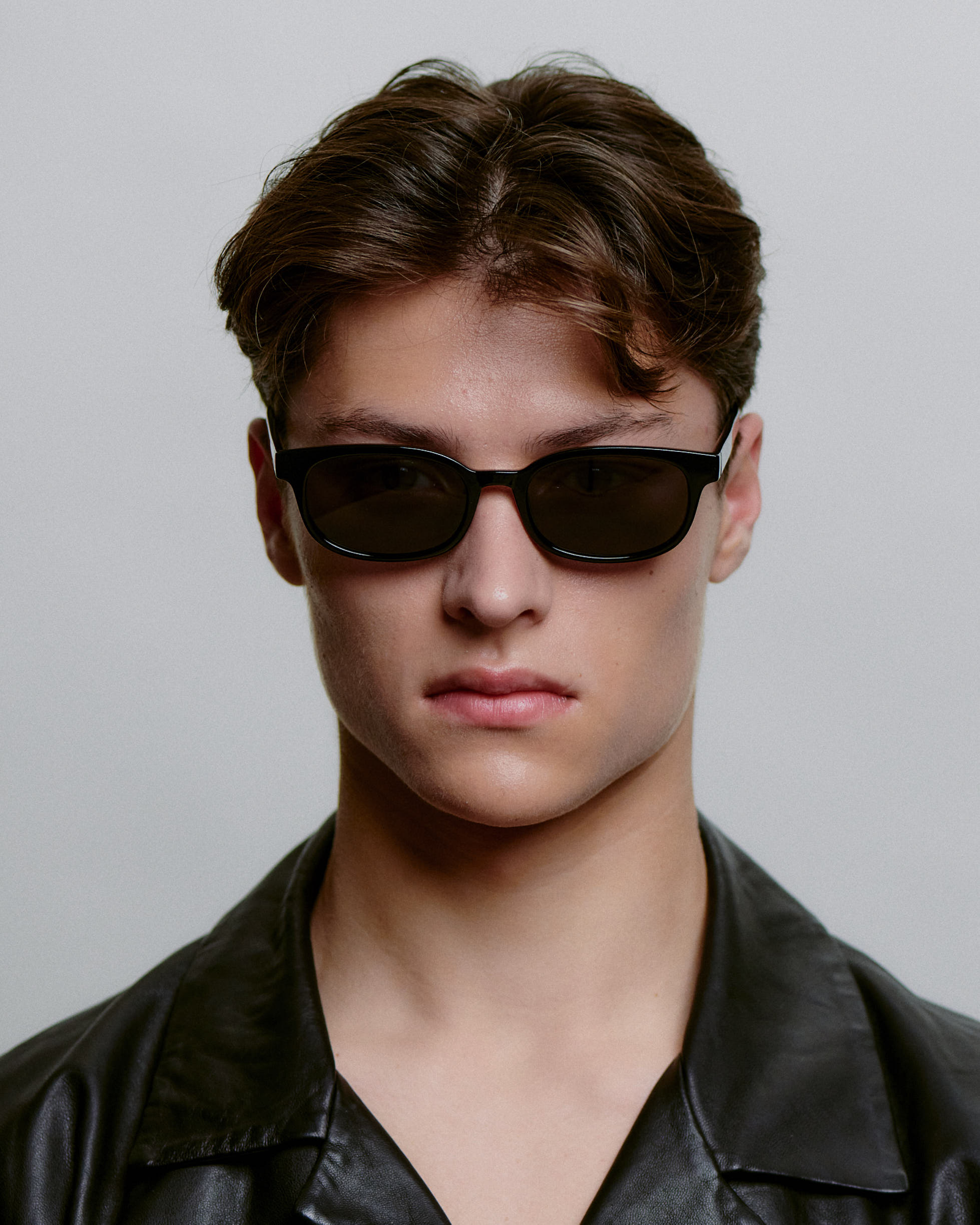 A.Kjærbede sorte solbriller med mørk glas foran på herre